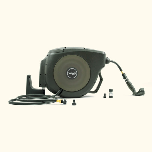 Green retractable garden hose reel mounted on a wooden wall with coiled hose and spray nozzle