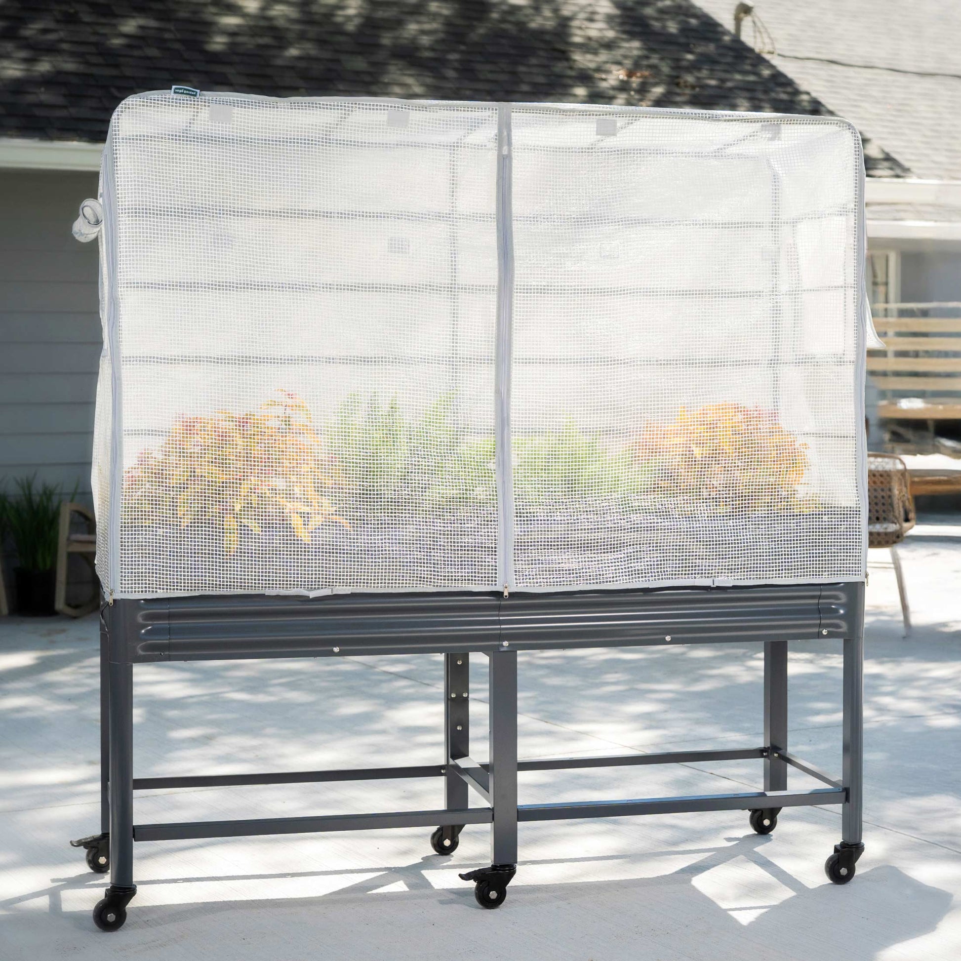 Green frost cover and trellis system attached to an elevated garden bed protecting plants from cold