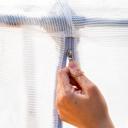 Ventilated mesh cover with zippered seams fitted over outdoor plant bed to protect from pests and weather