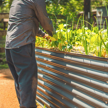 Extra-tall modular metal raised garden bed assembled outdoors with soil and edging panels