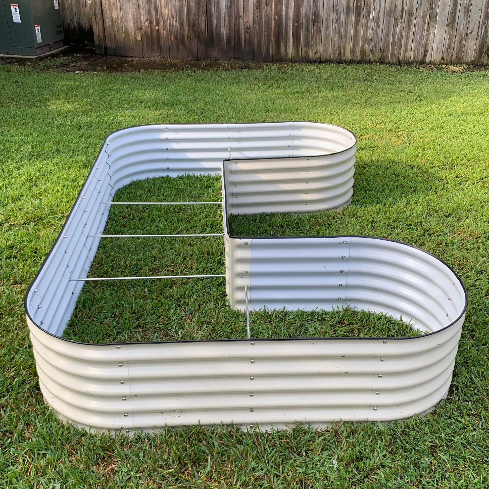 U-shaped 17-inch raised garden bed kit assembled outdoors with soil and mixed herbs planted inside