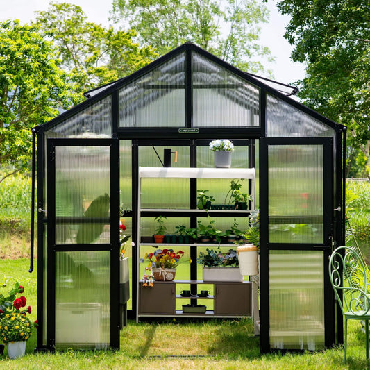 Victorian-style glass greenhouse 8.5 ft wide with peaked roof, decorative trim, and double doors surrounded by garden plants